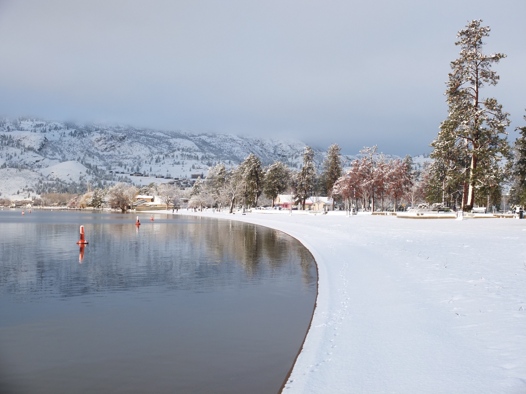Snowy Penticton lakeshore with Okanagan hills in winter.
